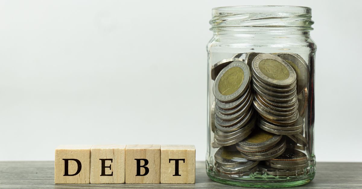 debt spelled out and jar of coins